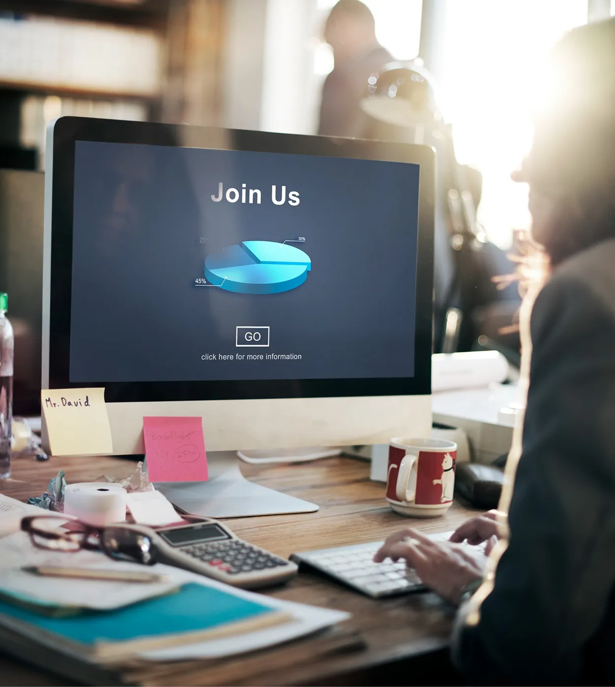 Computer monitor on a busy desk showing a dark 'Join Us' signup screen.